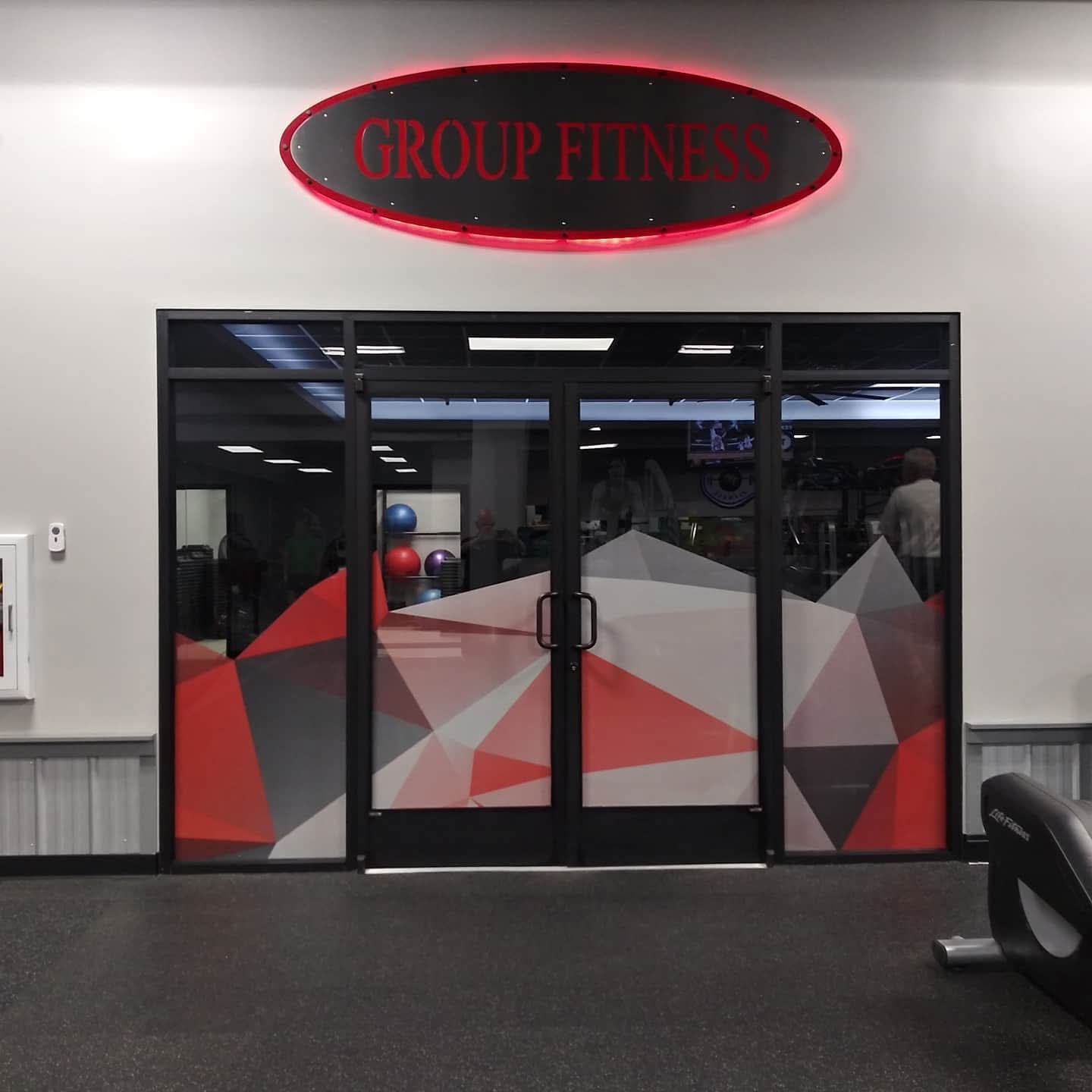 Gym entry doors and sidelights covered in red and grey geometric printed window film