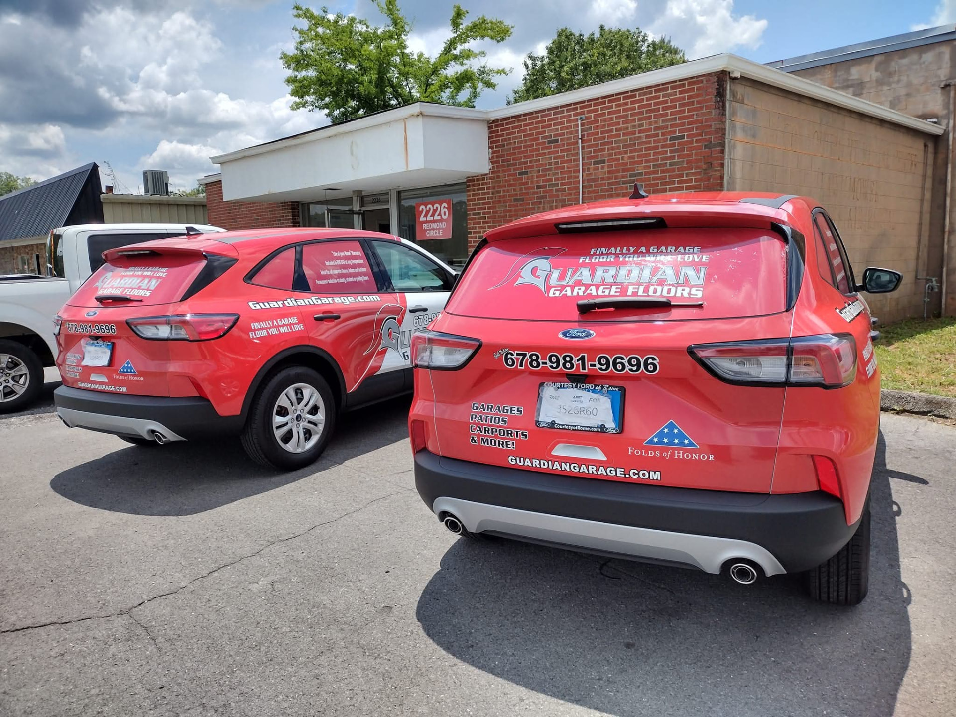 Two red Ford Escape SUVs wrapped with matching Guardian Garage Floors graphics
