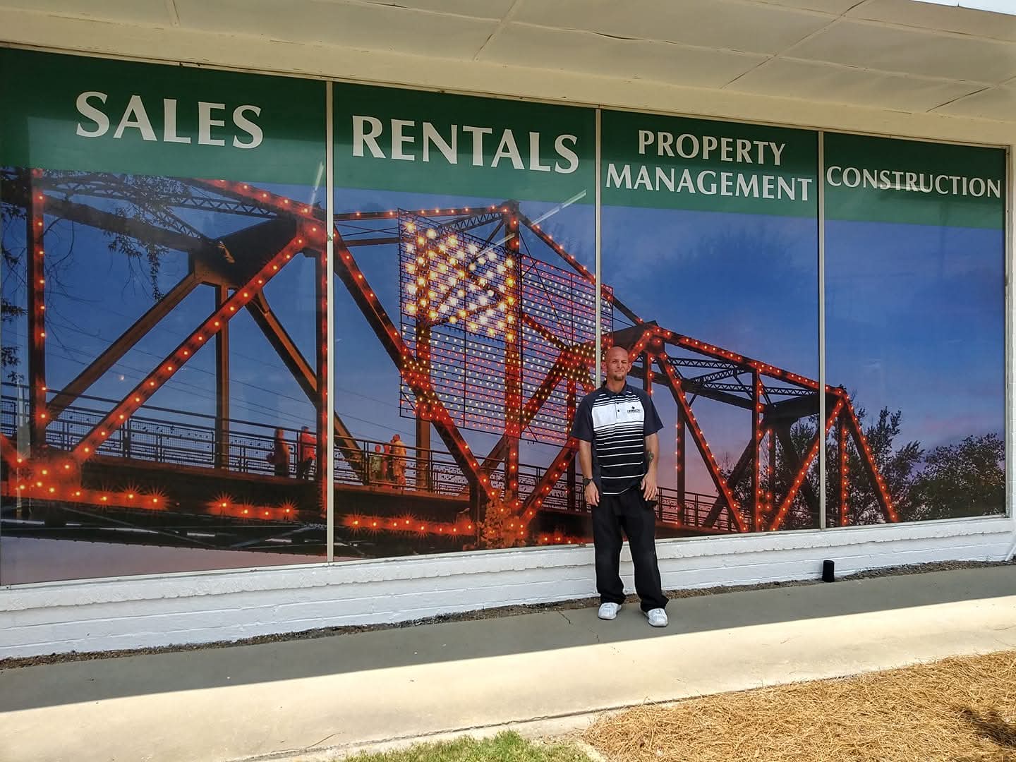 Storefront windows wrapped with a lit bridge photo and service headings
