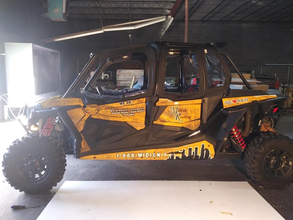 Polaris RZR side-by-side wrapped in black and distressed gold Midian Roofing graphics