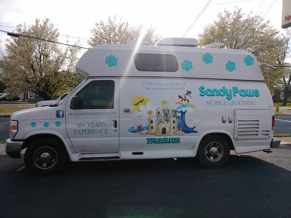 Sandy Paws Mobile Grooming van with teal paw prints and beach artwork