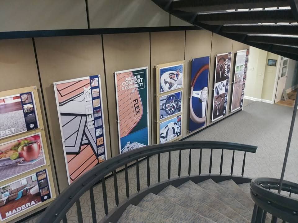 Curved staircase wall lined with large framed product displays and branded graphics
