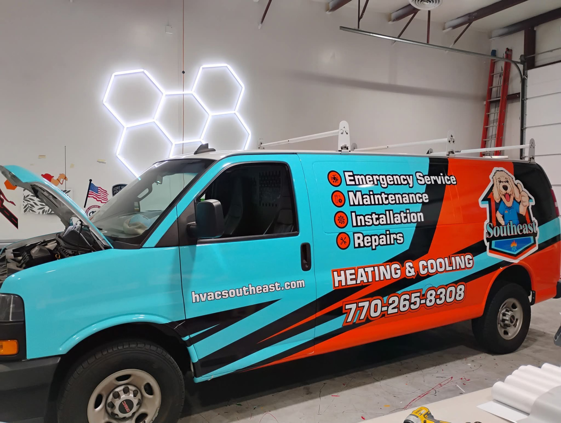 Teal and orange wrapped HVAC service van inside an install bay