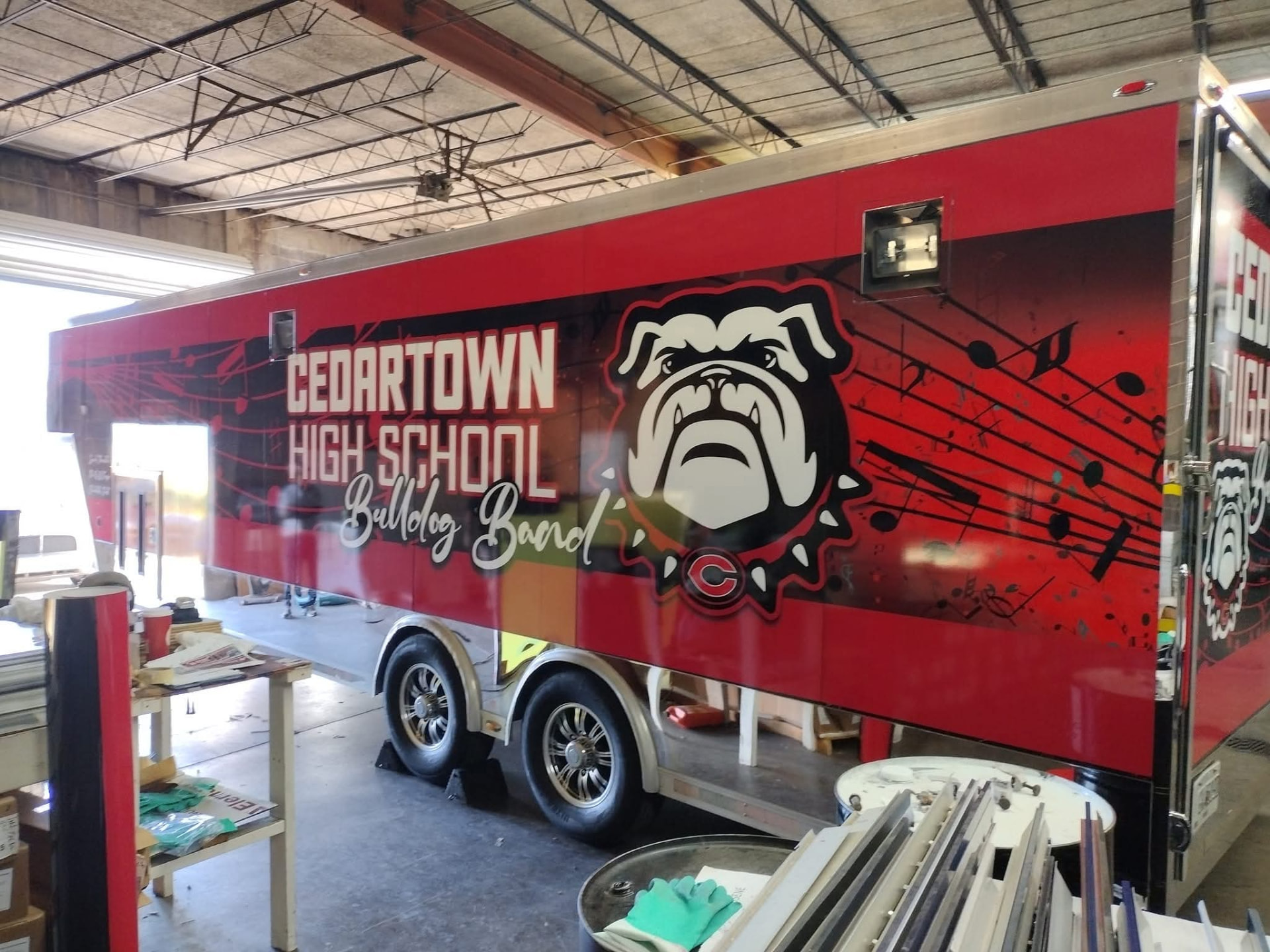 Red Cedartown High School Bulldog Band trailer wrap being installed indoors