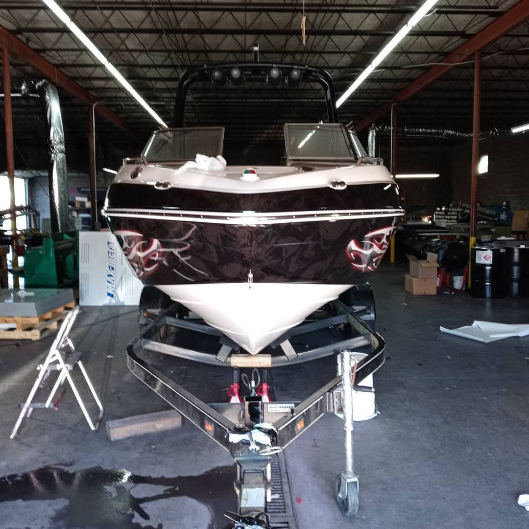 Bowrider boat hull wrapped in dark camo with red flame graphics on a trailer